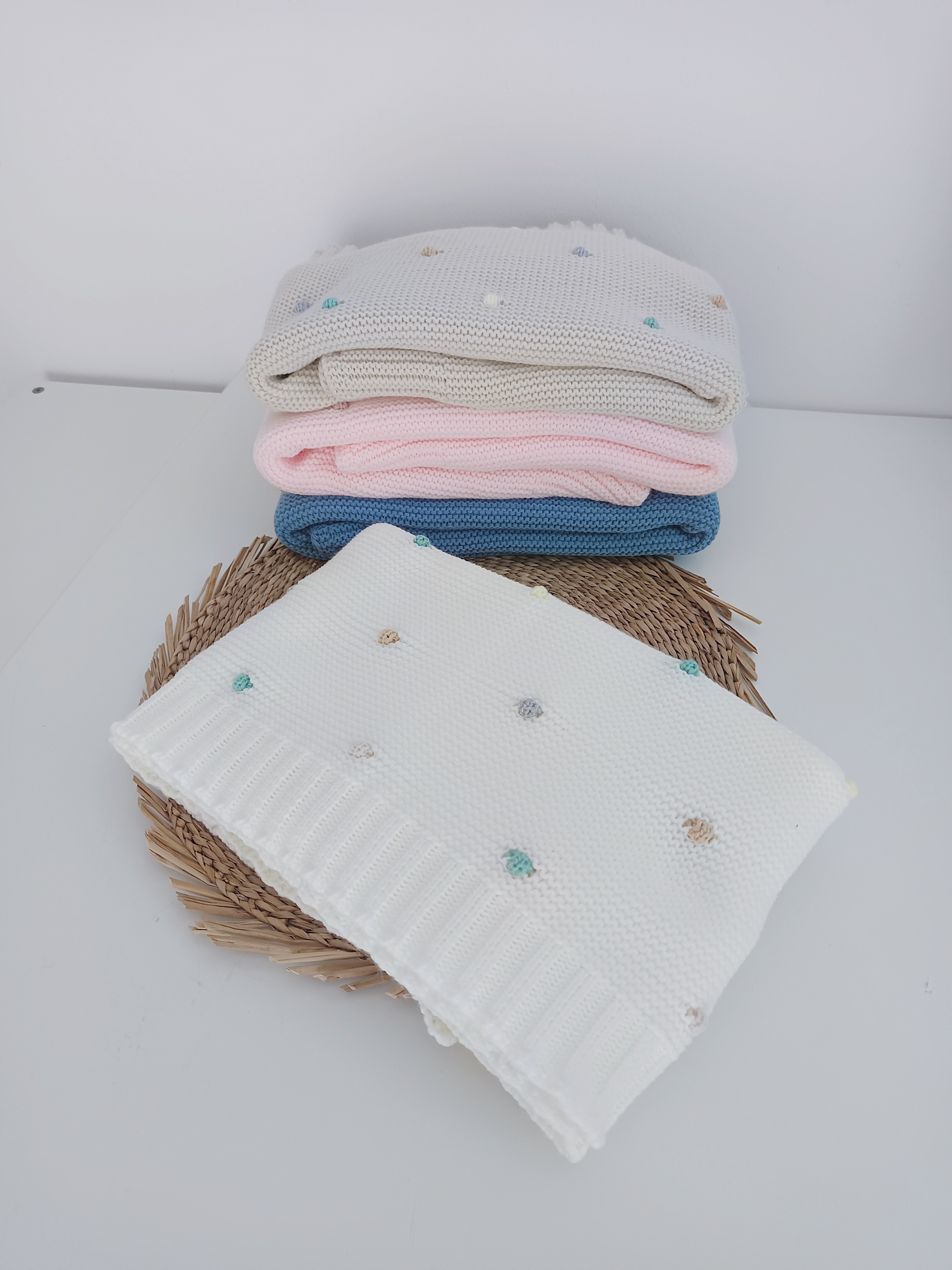 Detalhe pompons coloridos em manta de malha 100% acrílico para bebé, textura suave e confortável