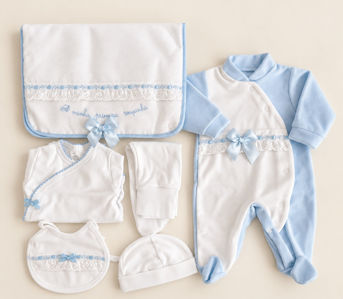 Conjunto de primeira roupinha para recém-nascido em branco e azul-claro, com babygrow de veludo, body, calcinhas, gorro, babete e bolsa decorados com fitas azuis, renda e laços.
