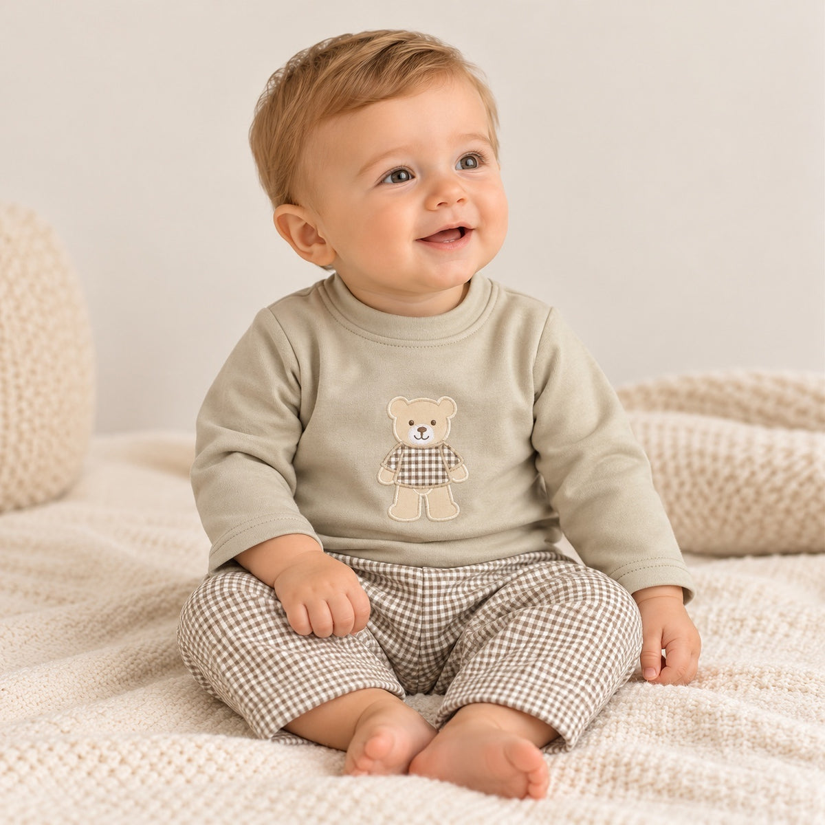 Conjunto de bebé com camisola areia de manga comprida e aplicação de urso, combinado com calças forradas de padrão vichy bege e branco.
