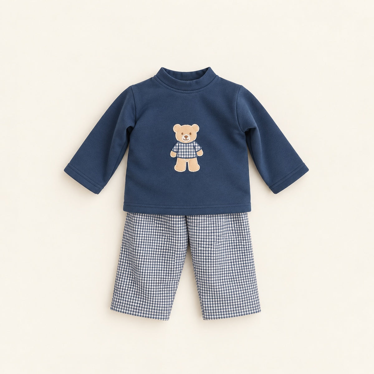 Conjunto de bebé com camisola azul-marinho de manga comprida e aplicação de urso, combinado com calças forradas de padrão vichy azul e branco.