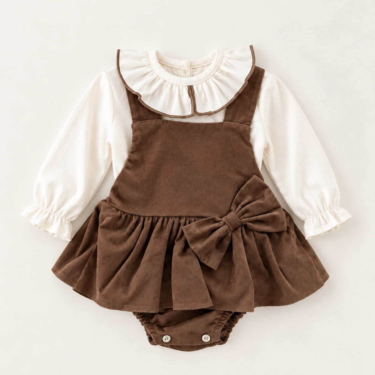 Fofo castanho com saia franzida e laço lateral, combinado com blusa branca de manga comprida, gola com folho e punhos franzidos.