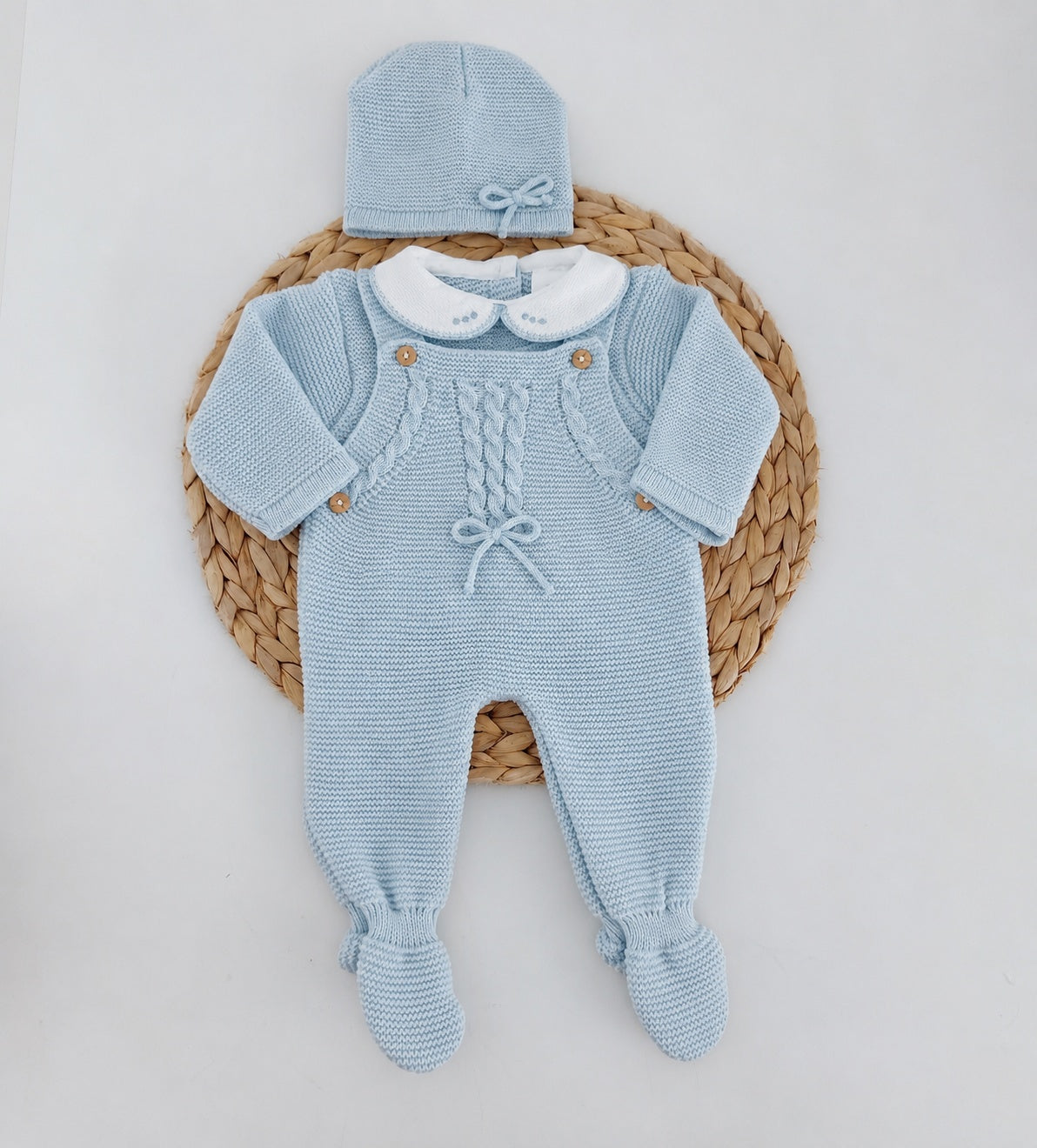 Jardineiras de malha azul para bebé com camisola de gola branca, trancinhas e gorro a combinar